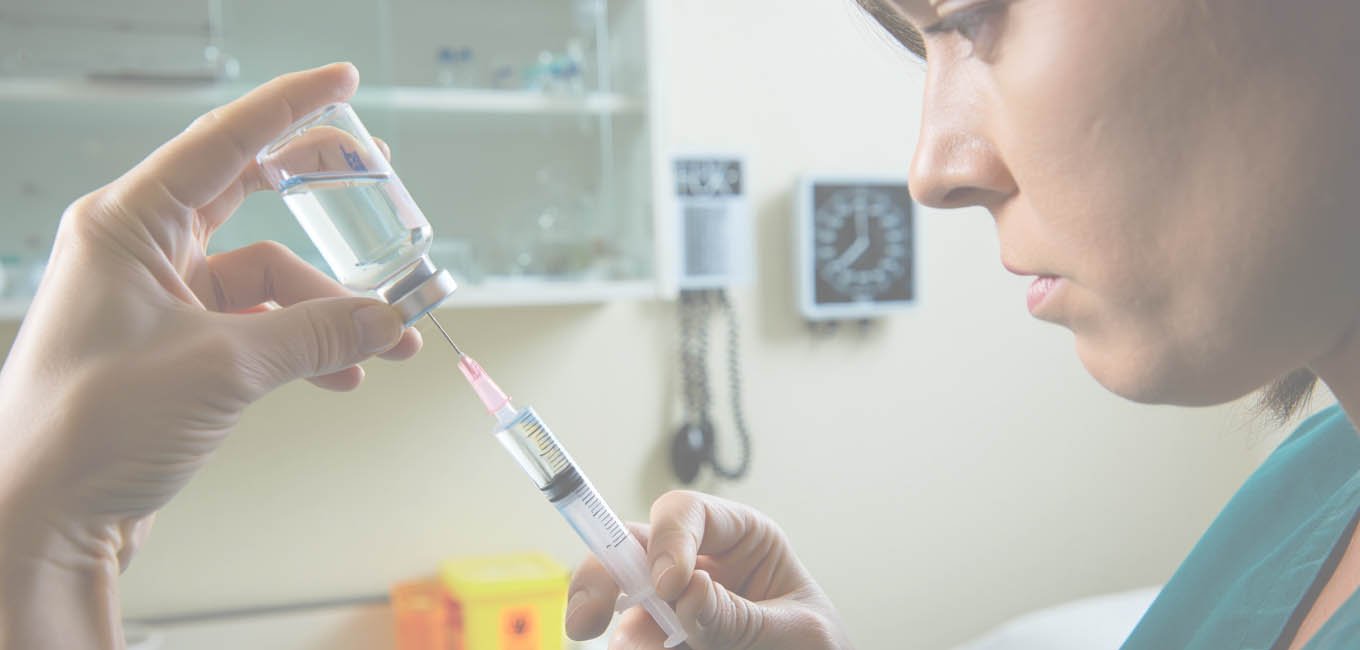 Женщина врач подготавливает шприц с лекарством.